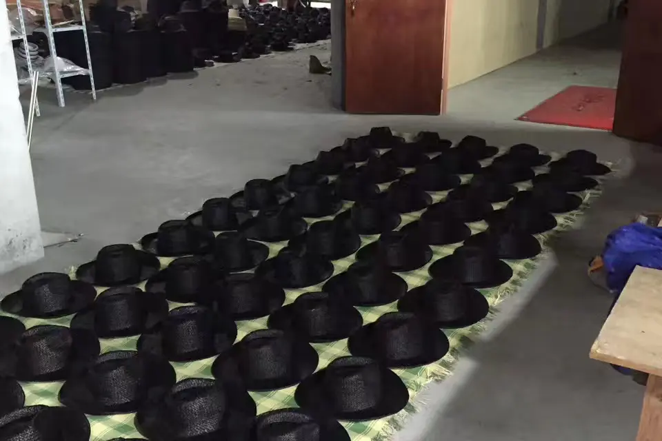 Rows of black woven hats in a factory production batch