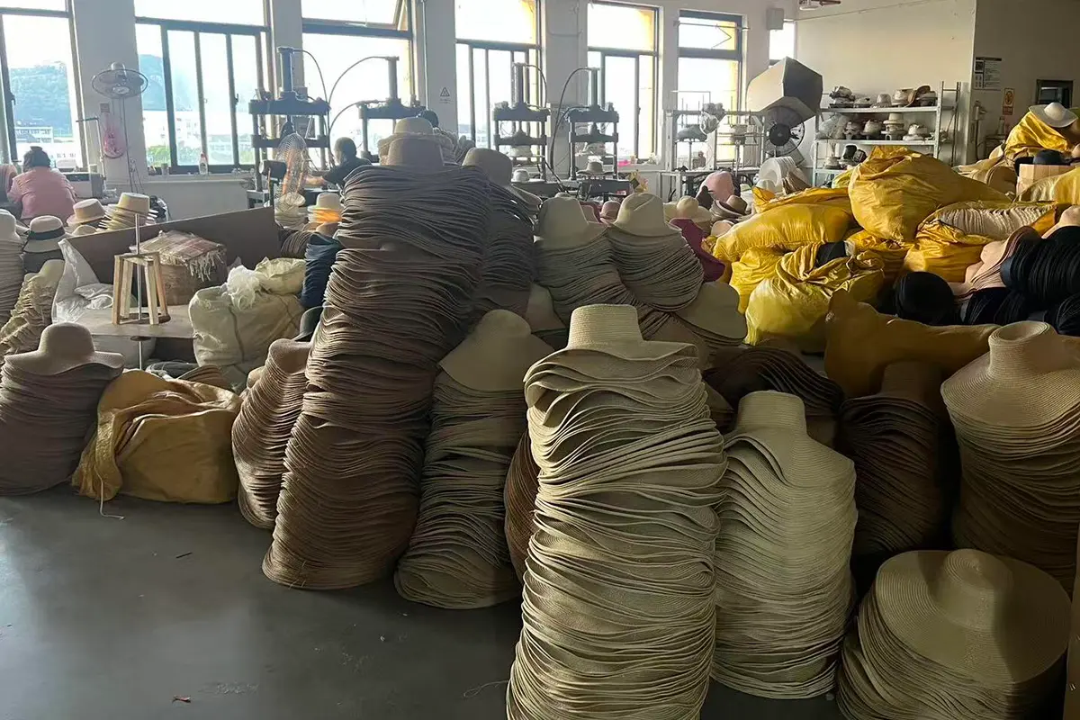 Large stacks of assorted straw hat bodies inside the workshop