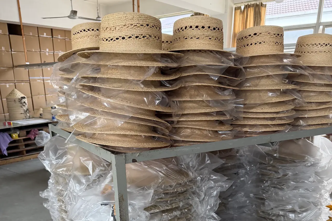Openwork boater hats protected in large stacks in the workshop