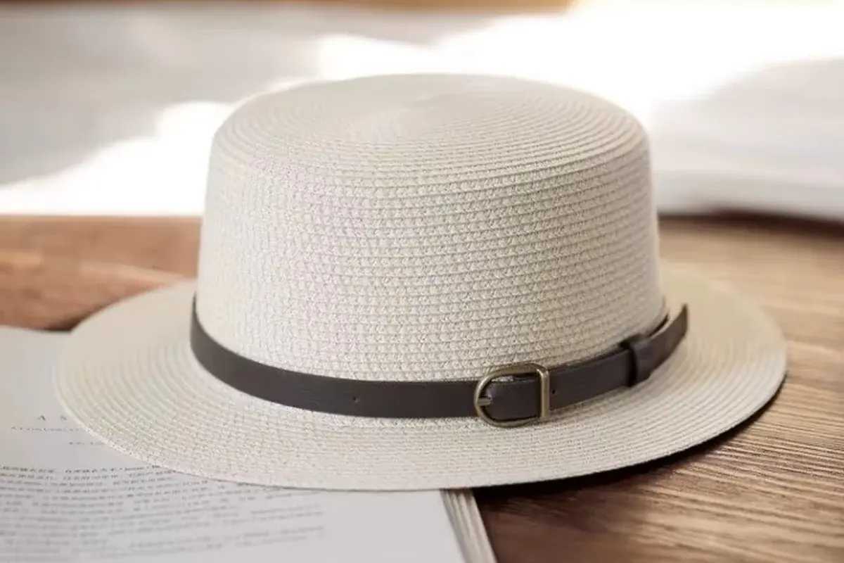 White boater hat with a clean brown band and buckle detail