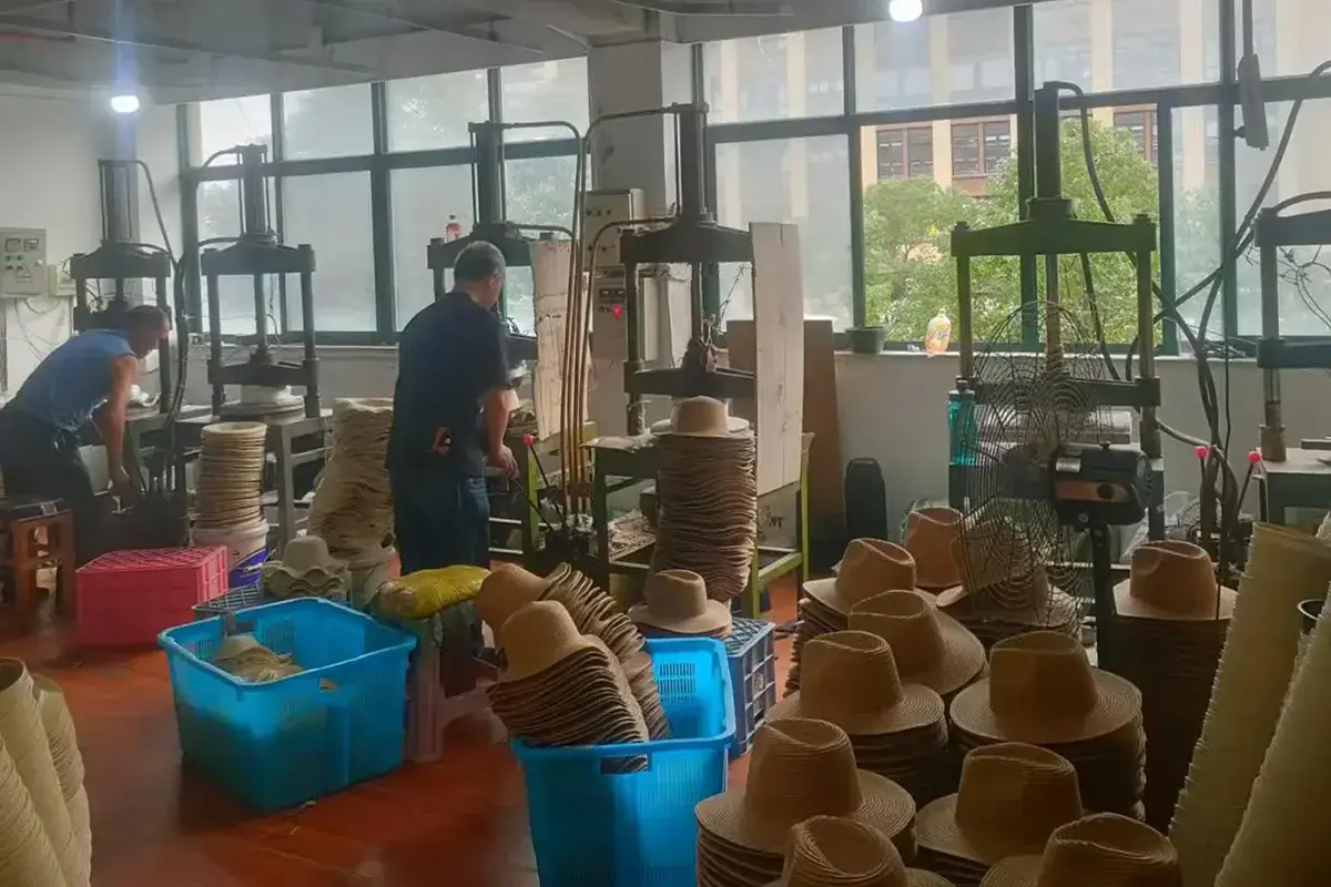Factory team shaping structured straw hat bodies with production equipment