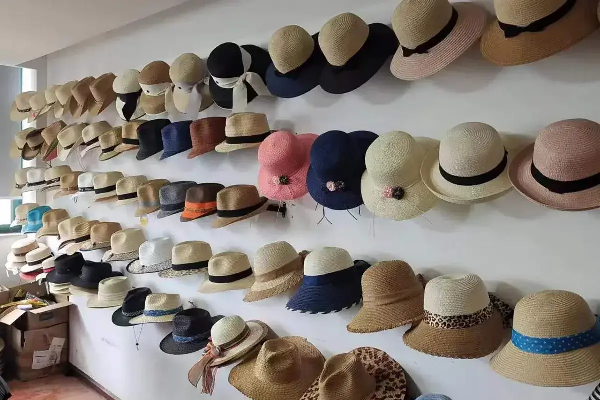 Straw hat samples displayed across the factory sample-room wall