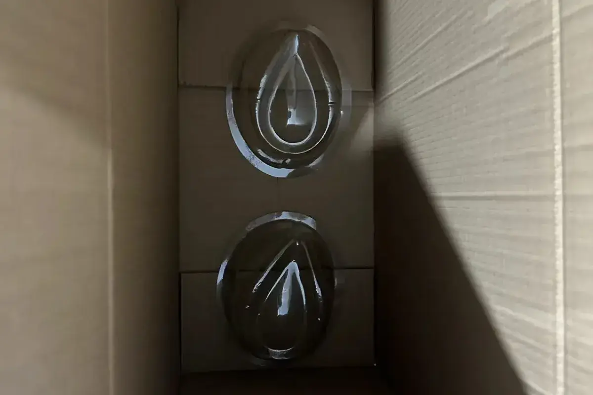 Two clear cord adjusters prepared for straw hat component sampling