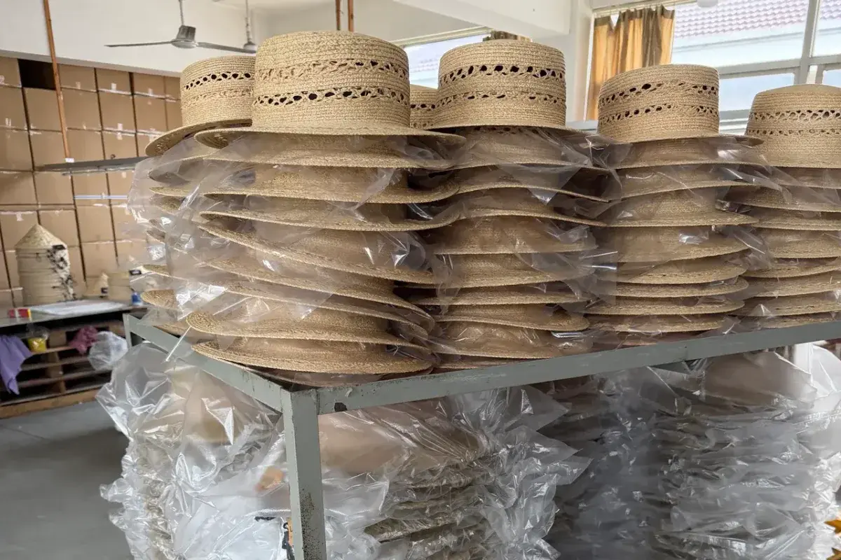Batches of natural wide-brim straw hats protected for production handling