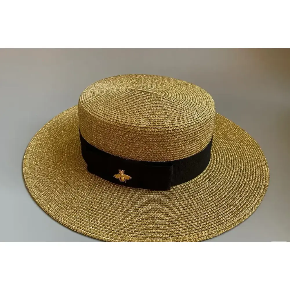 Gold Panama-style boater hat with a black band and decorative pin