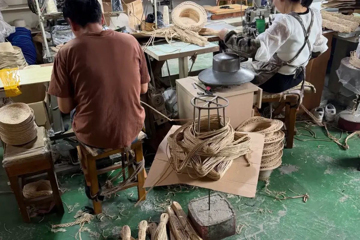 Workers shaping straw hat bodies in the production workshop