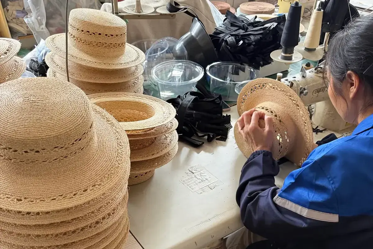 Worker finishing raffia hats during factory production