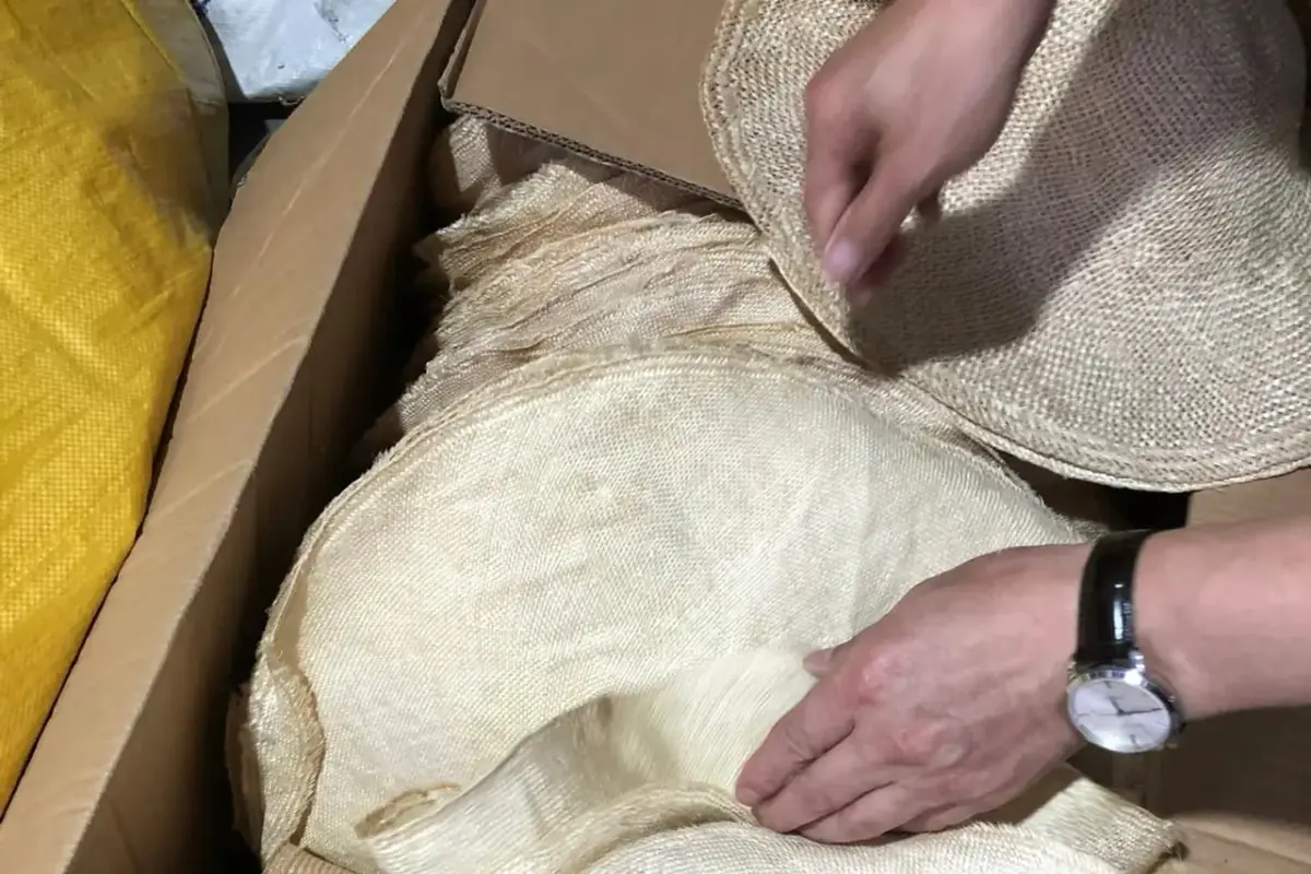 Hands checking raffia hat bodies during shape development