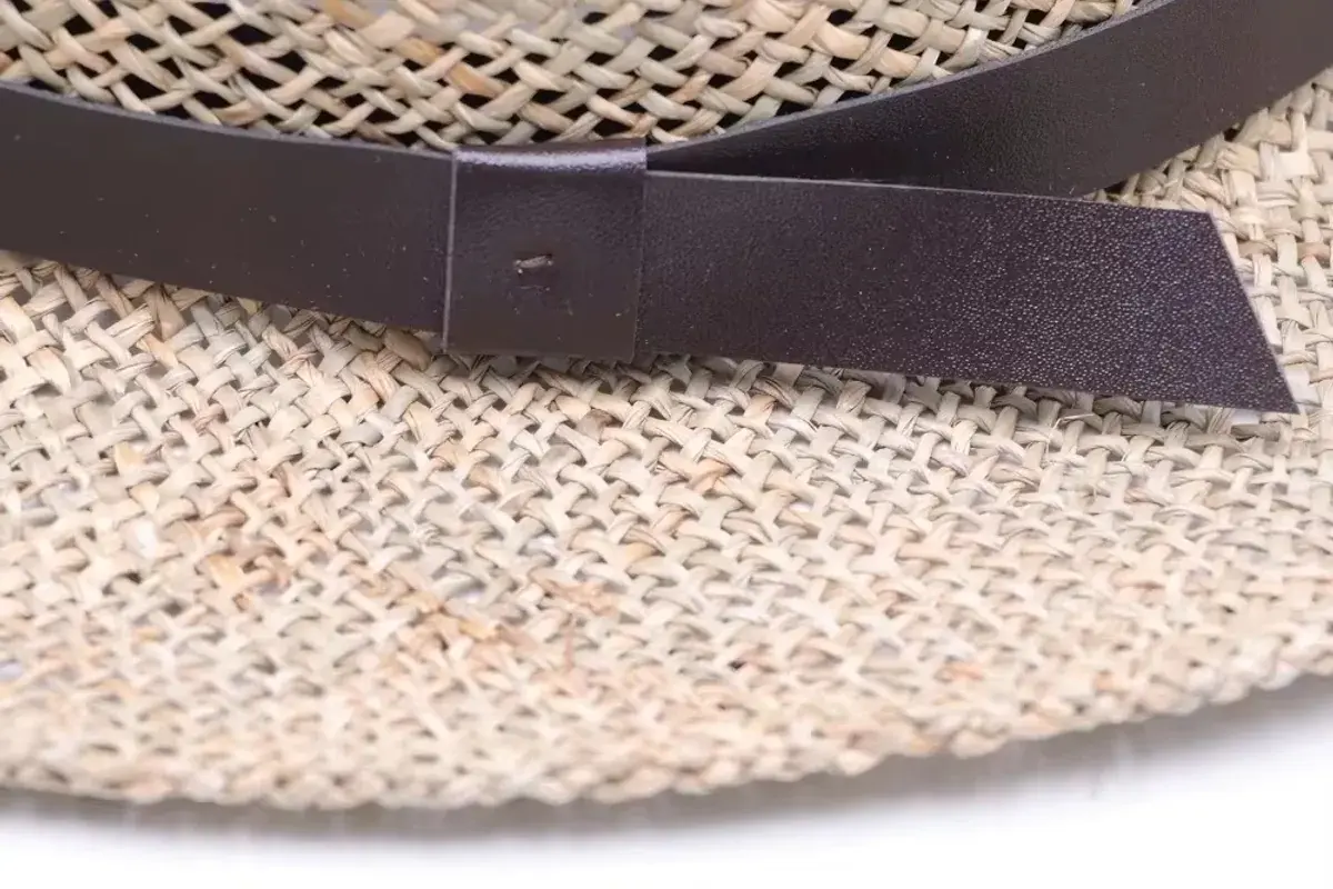 Close view of a dark ribbon band secured around woven straw