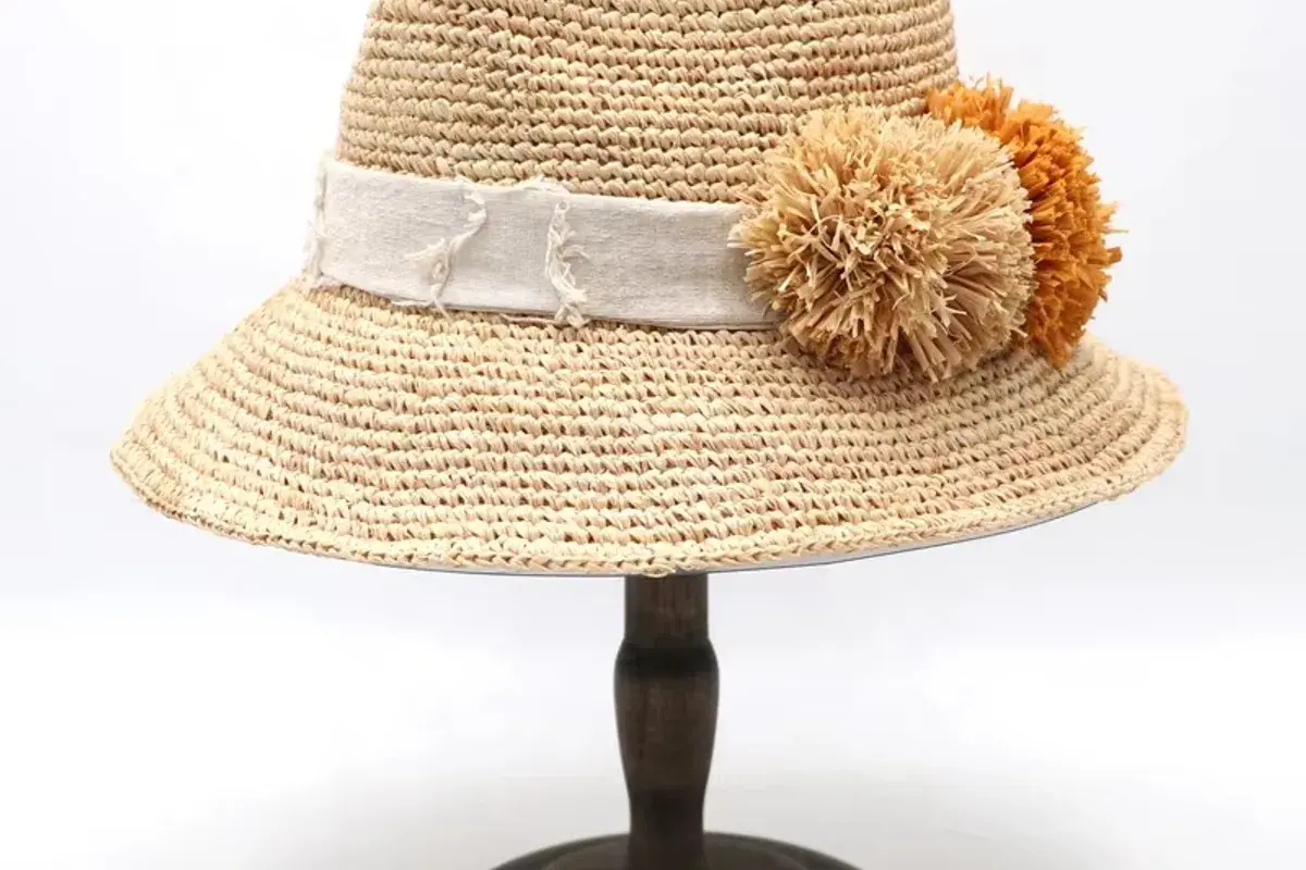 Natural straw fedora on a stand with layered ribbon and flower trim