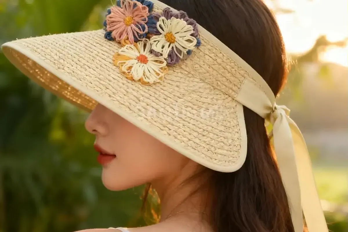 Woman wearing a wide-brim straw visor with a floral headband
