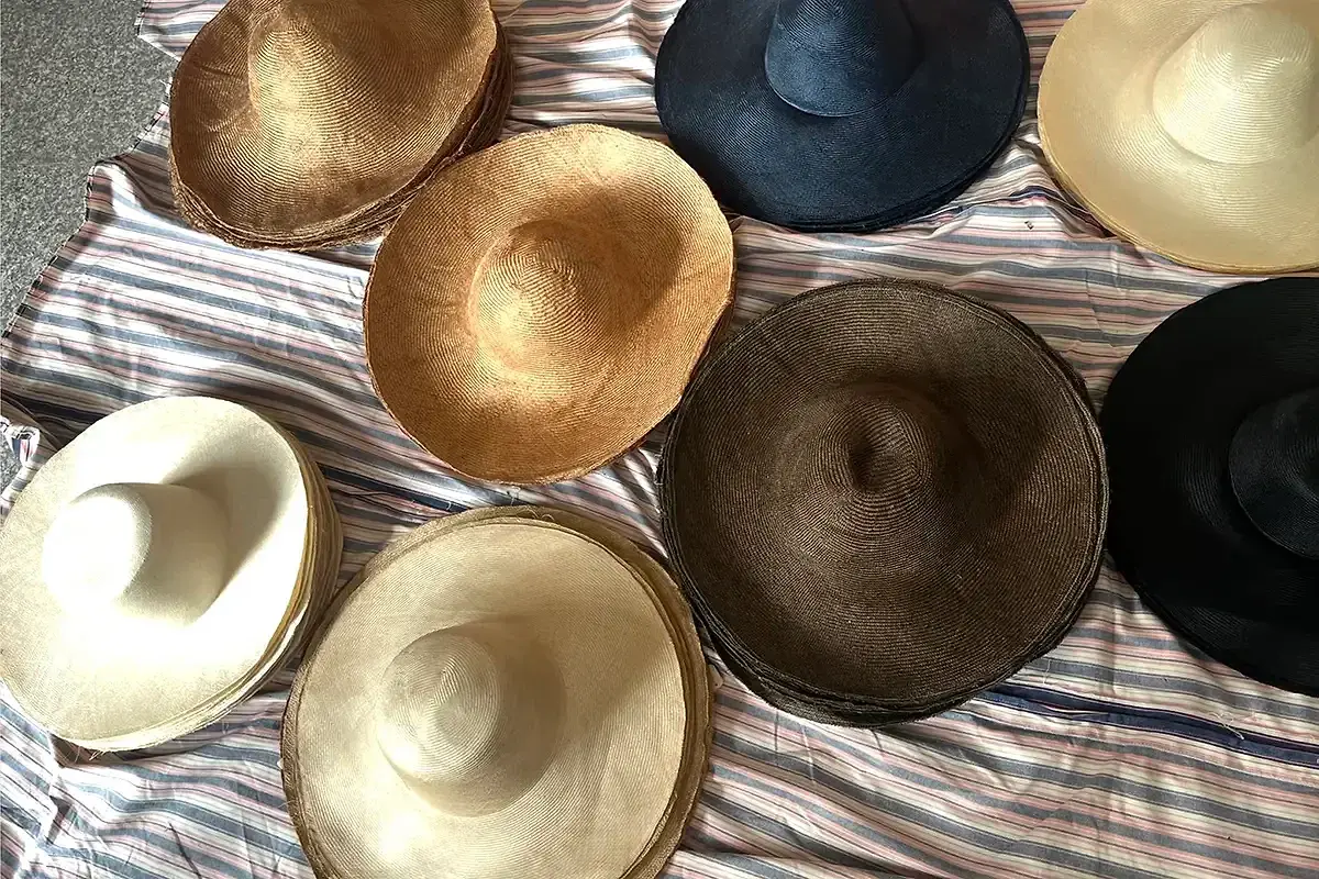 Metallic bronze, matte black, brown, and ivory straw hat bodies showing finish differences