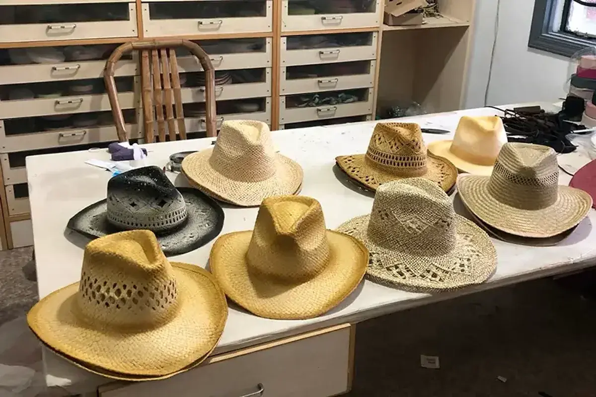 Factory table of straw cowboy hats showing warm, pale, dark, and gray natural tones