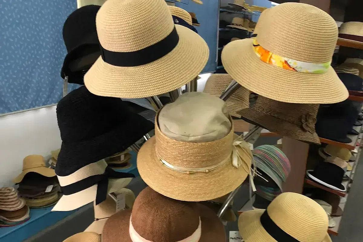 Factory straw hat samples comparing black, natural, and multicolor band combinations