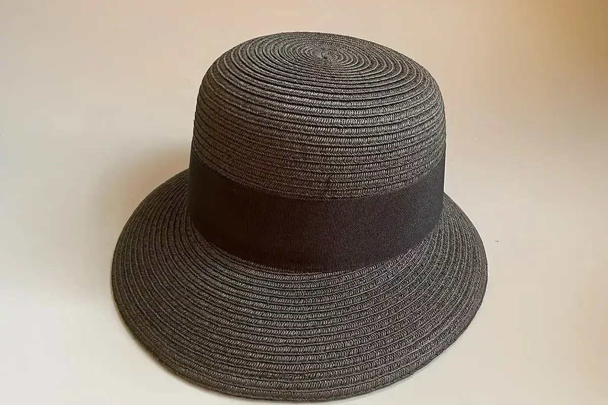 Gray straw hat with a wide smooth dark ribbon fitted level around the crown