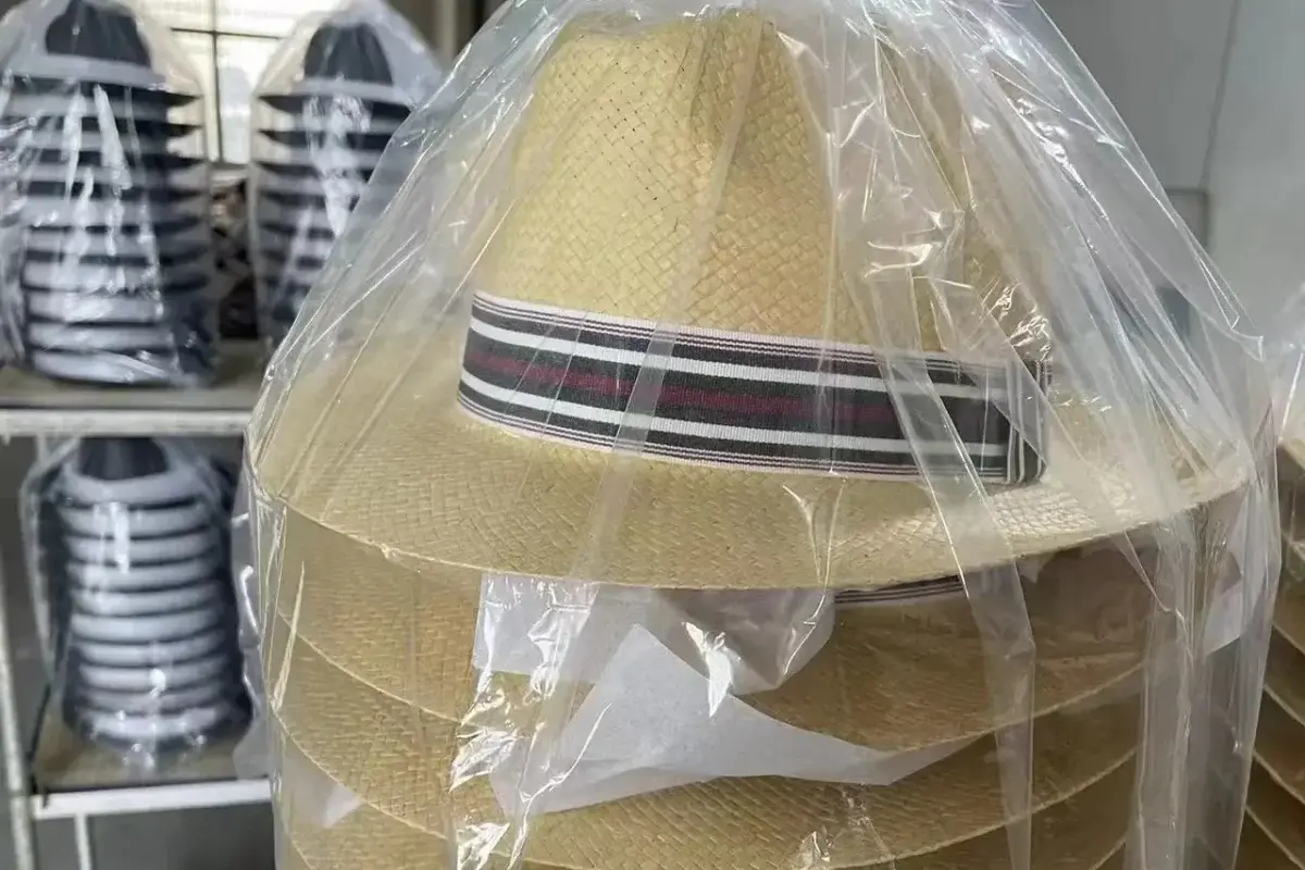 Finished straw hats protected by clear bagging and tissue between layers