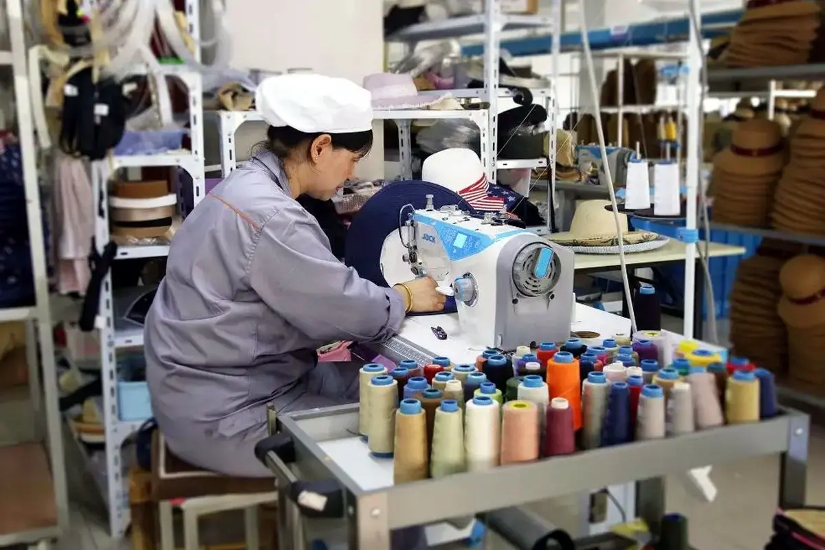 Factory worker preparing straw hat logo embroidery with multiple thread colors