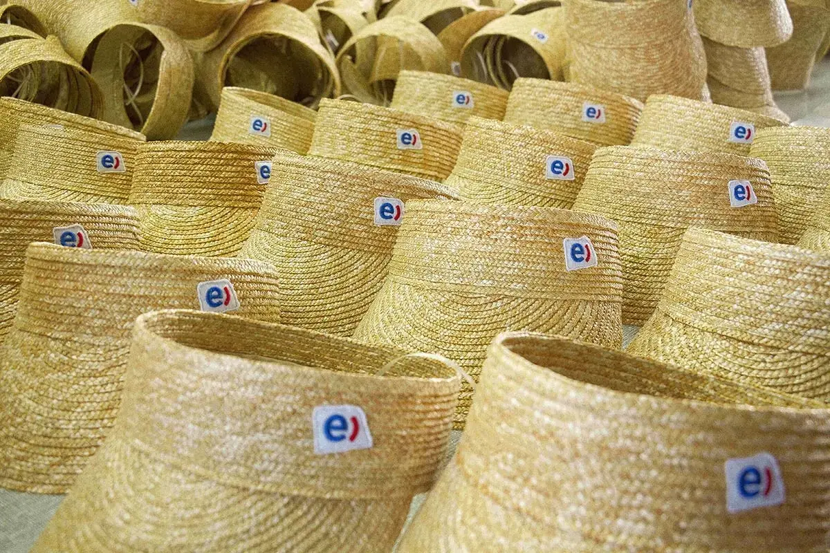 Factory batch of straw hat crowns with mounted woven logo patches