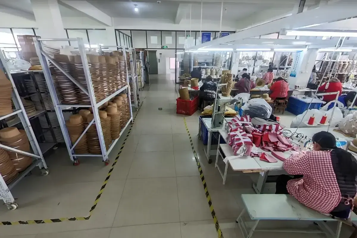 Straw hat workers, material racks, and assembly stations on the factory floor