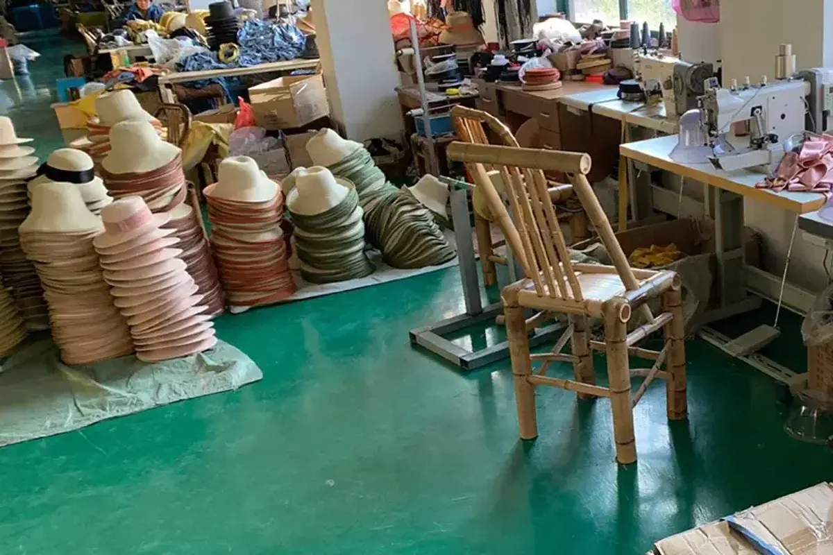 Straw hat bodies, sewing equipment, and workstations inside the custom hat factory